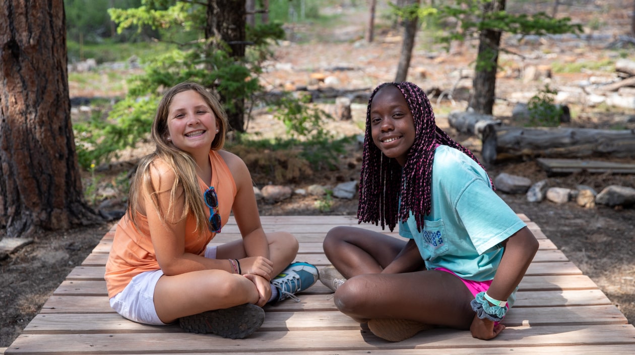 Two girls sitting and smiling.