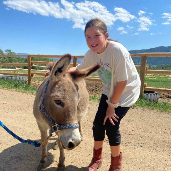 Girl posing with donkey.