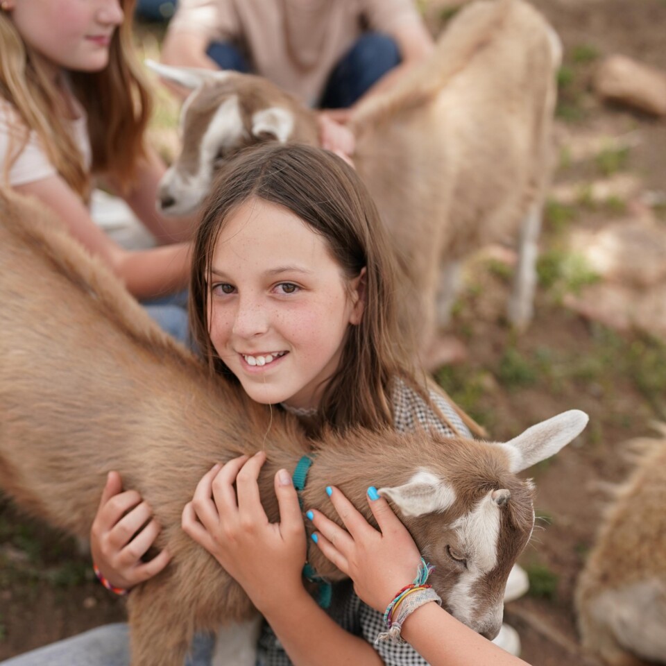 Girl smiling holding goat.