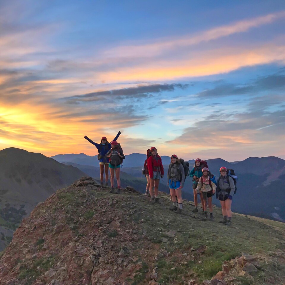 Kids hiking on mountain at sunset.