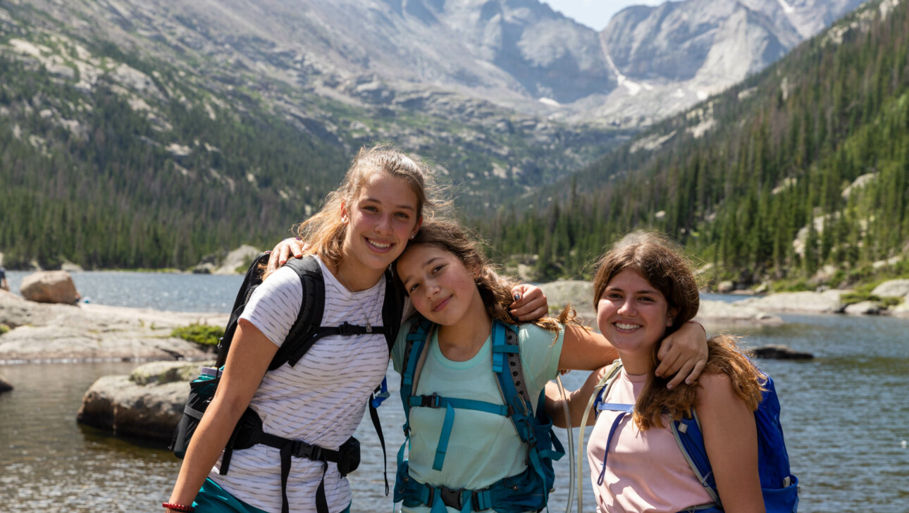 Girls hugging and smiling on mountain.