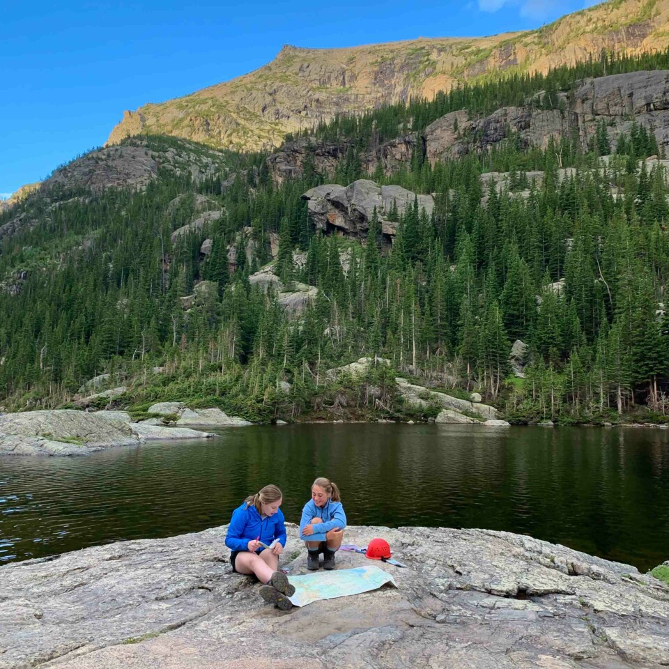 Two girls sitting on rock.