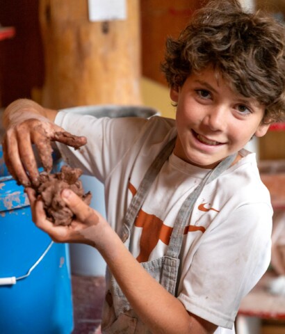 Boy holding clay smiling.