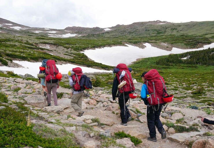 People backpacking with red backpacks.