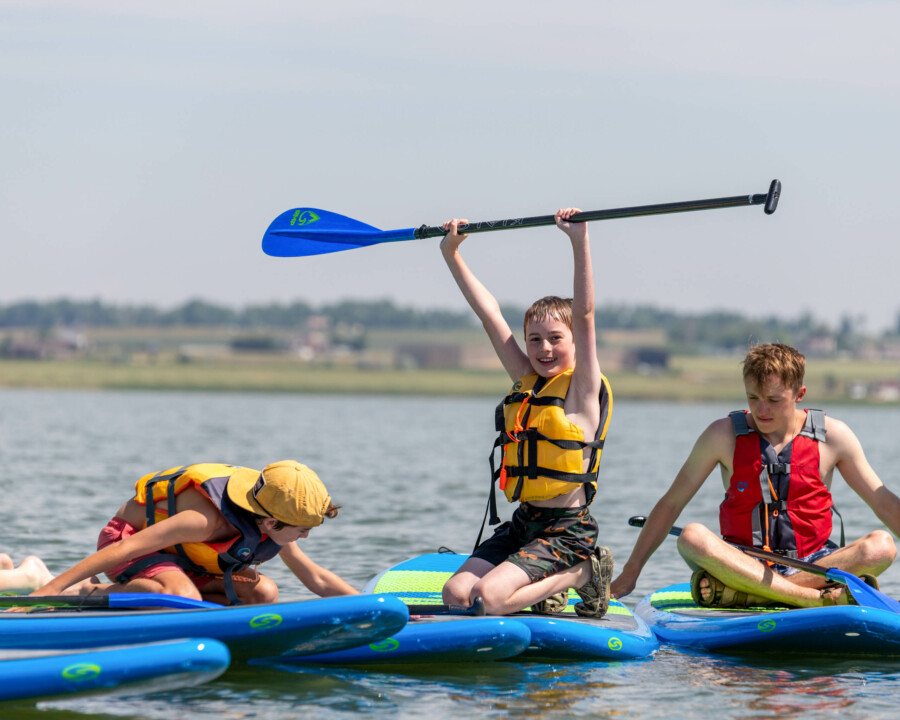 Boy holding up a paddle on board.