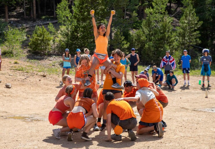 Orange team lifting up girl.