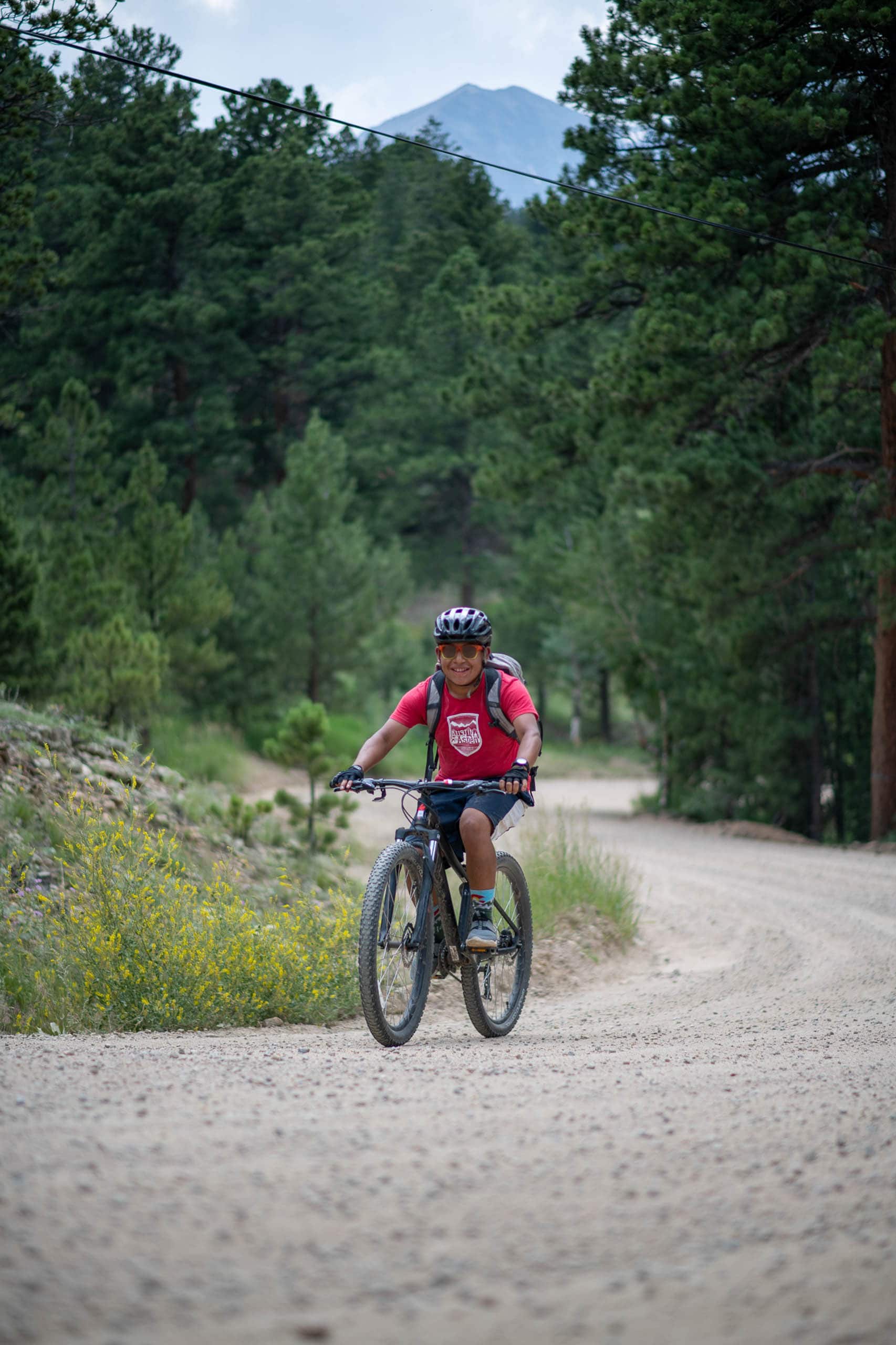 Camper riding mountain bike on dirt road.