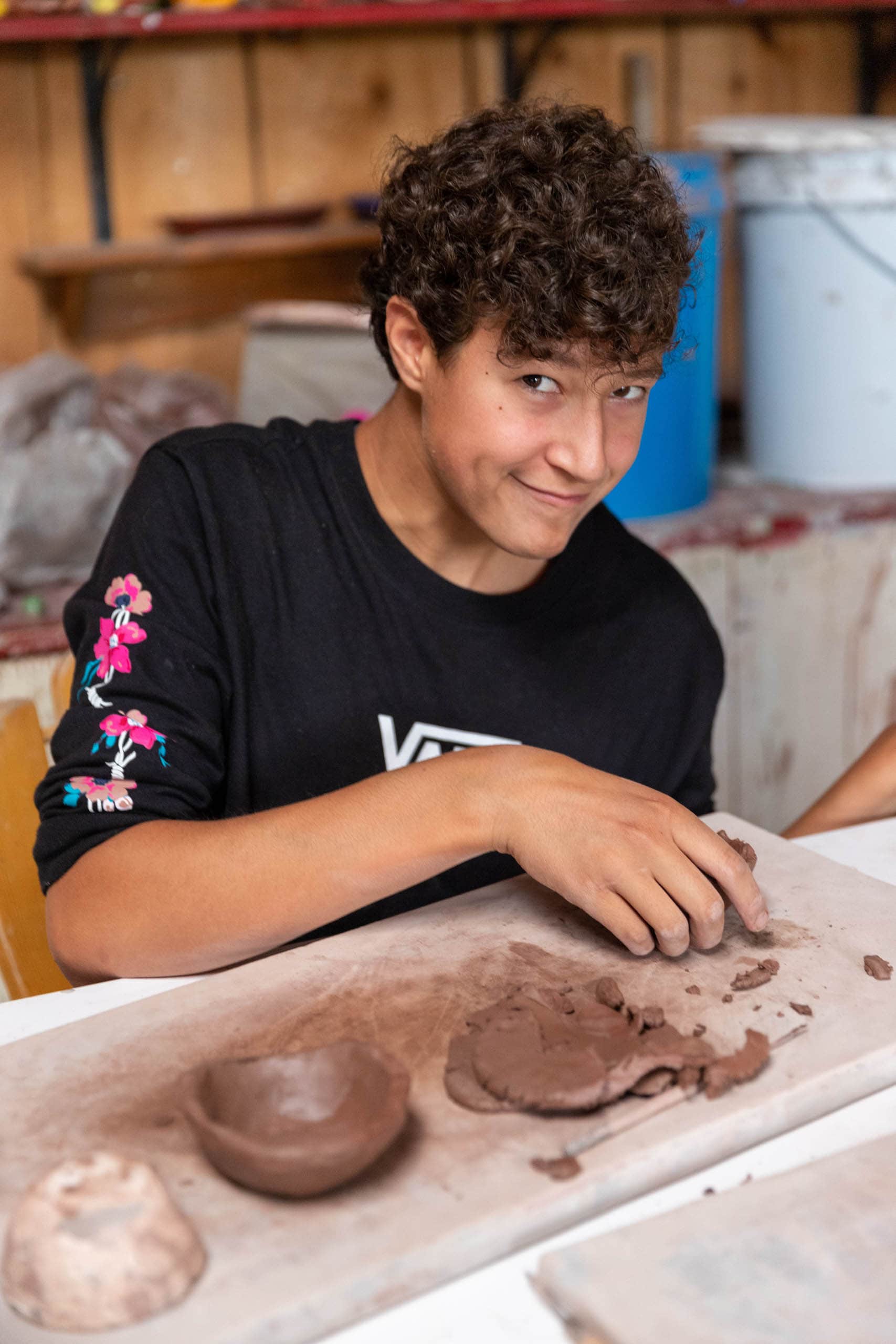 Boy camper working on hand building ceramics.