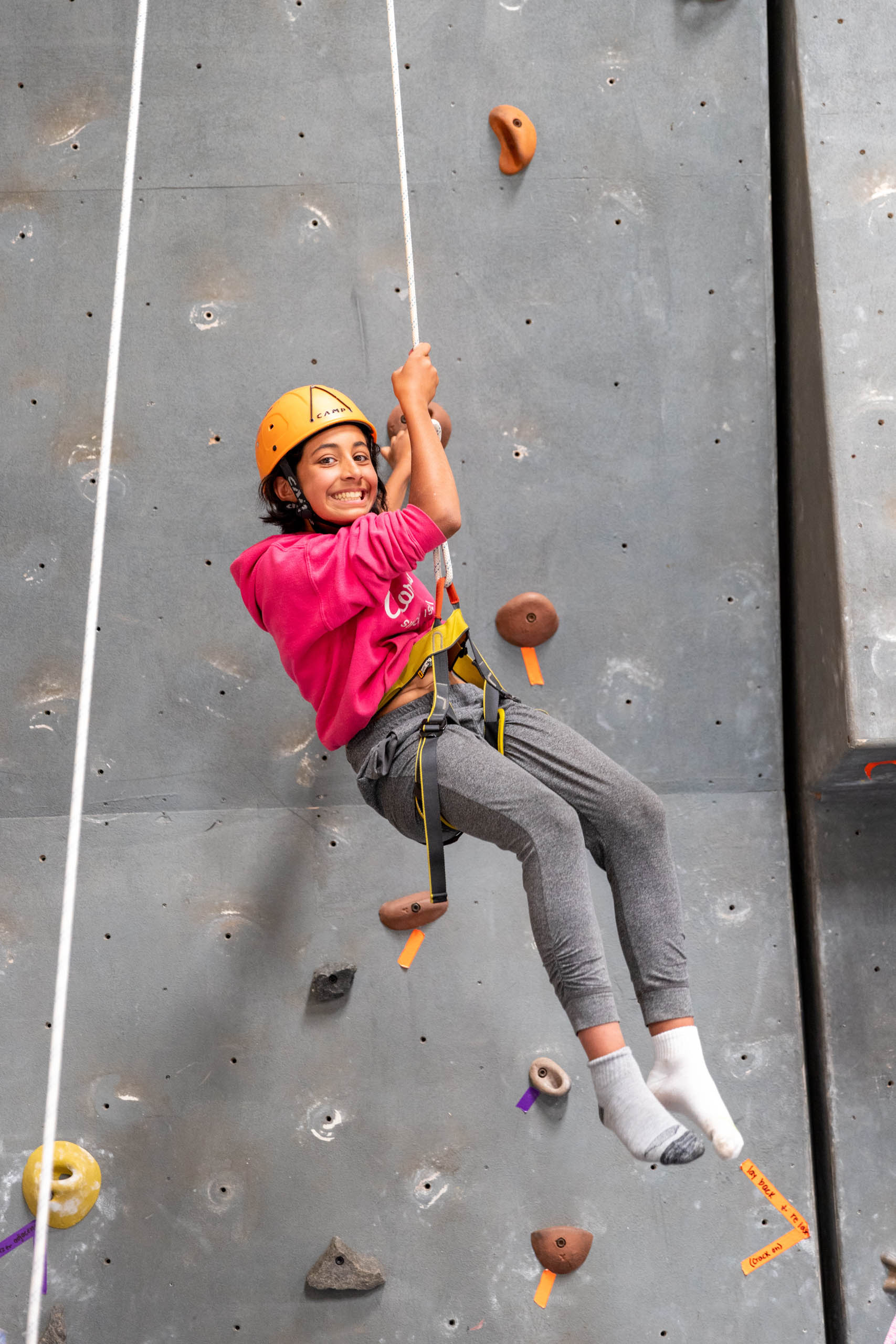 Camper hanging on the rope by the rock wall.