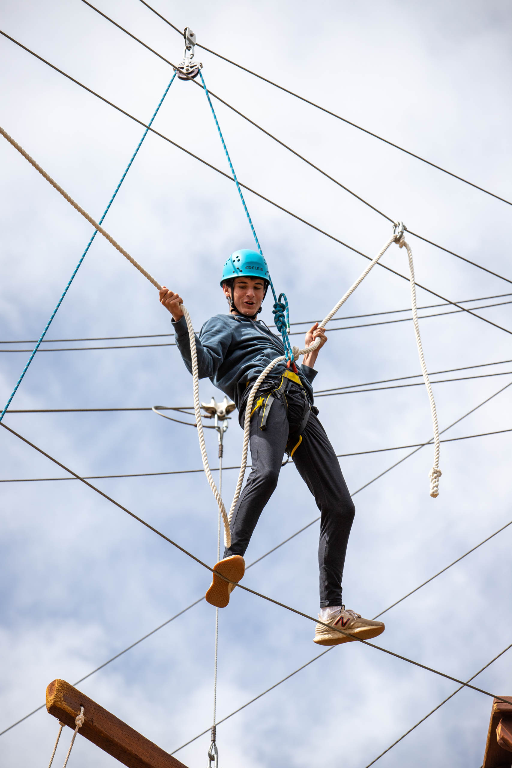 Male camper on the ropes course with a helmet.