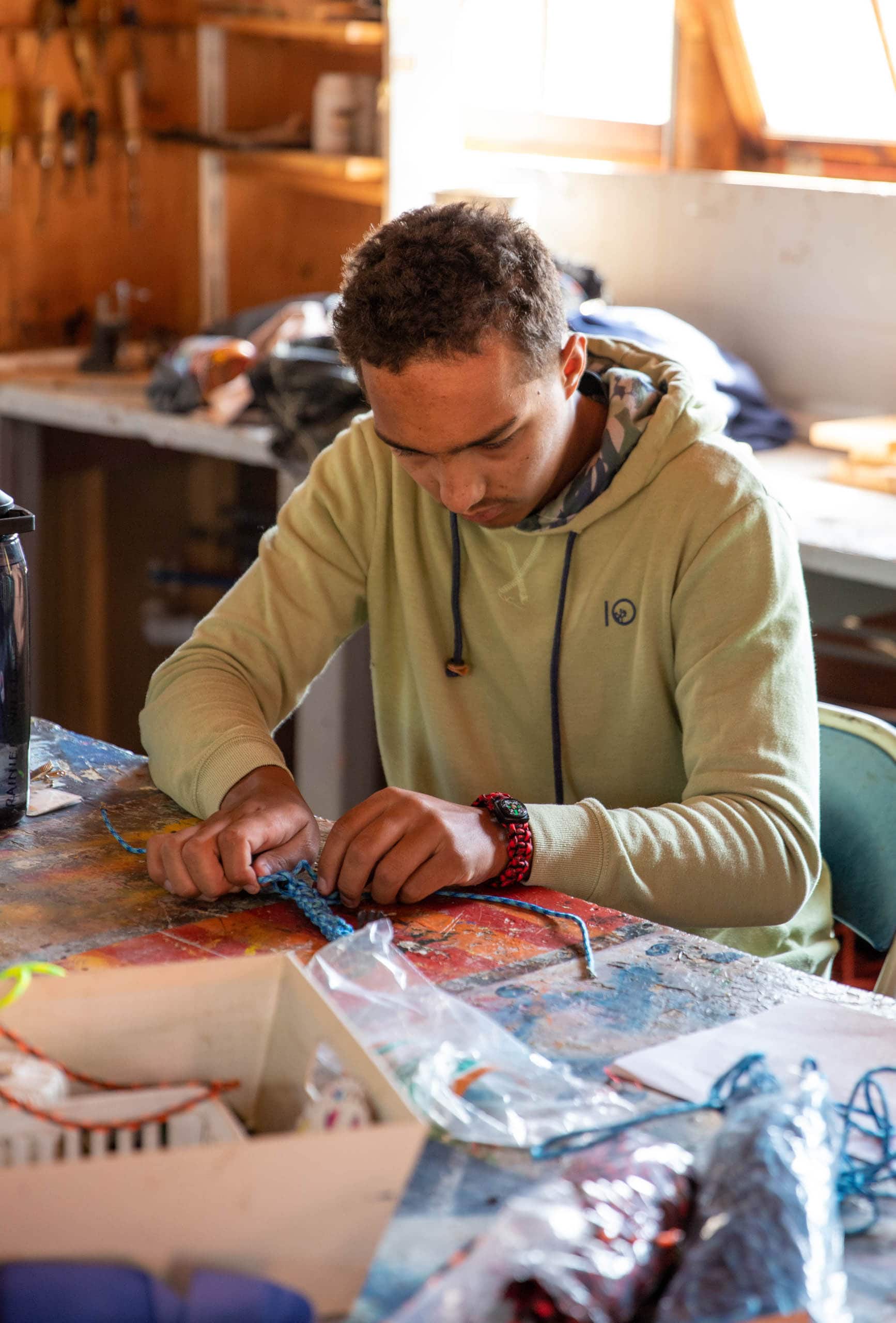 Camper making bracelets with rope.