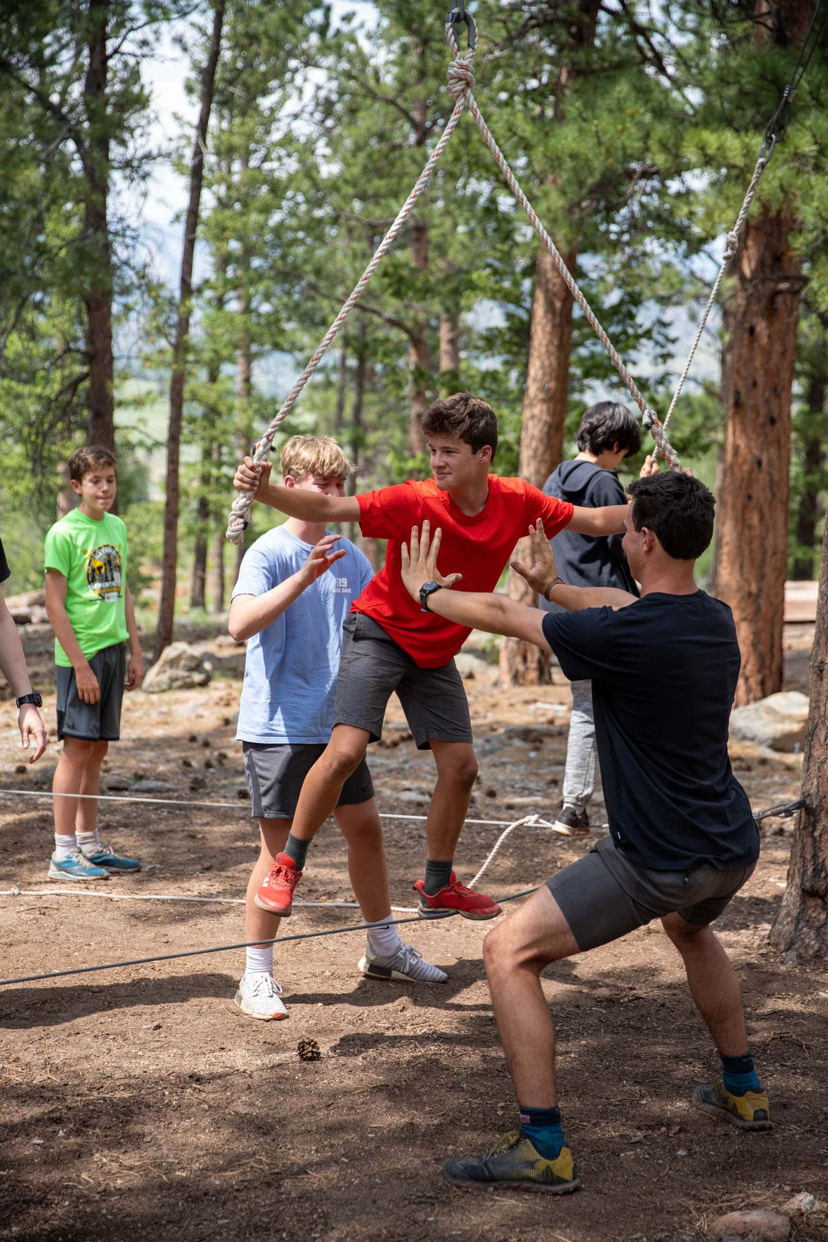 Campers helping a camper complete the rope balance course.