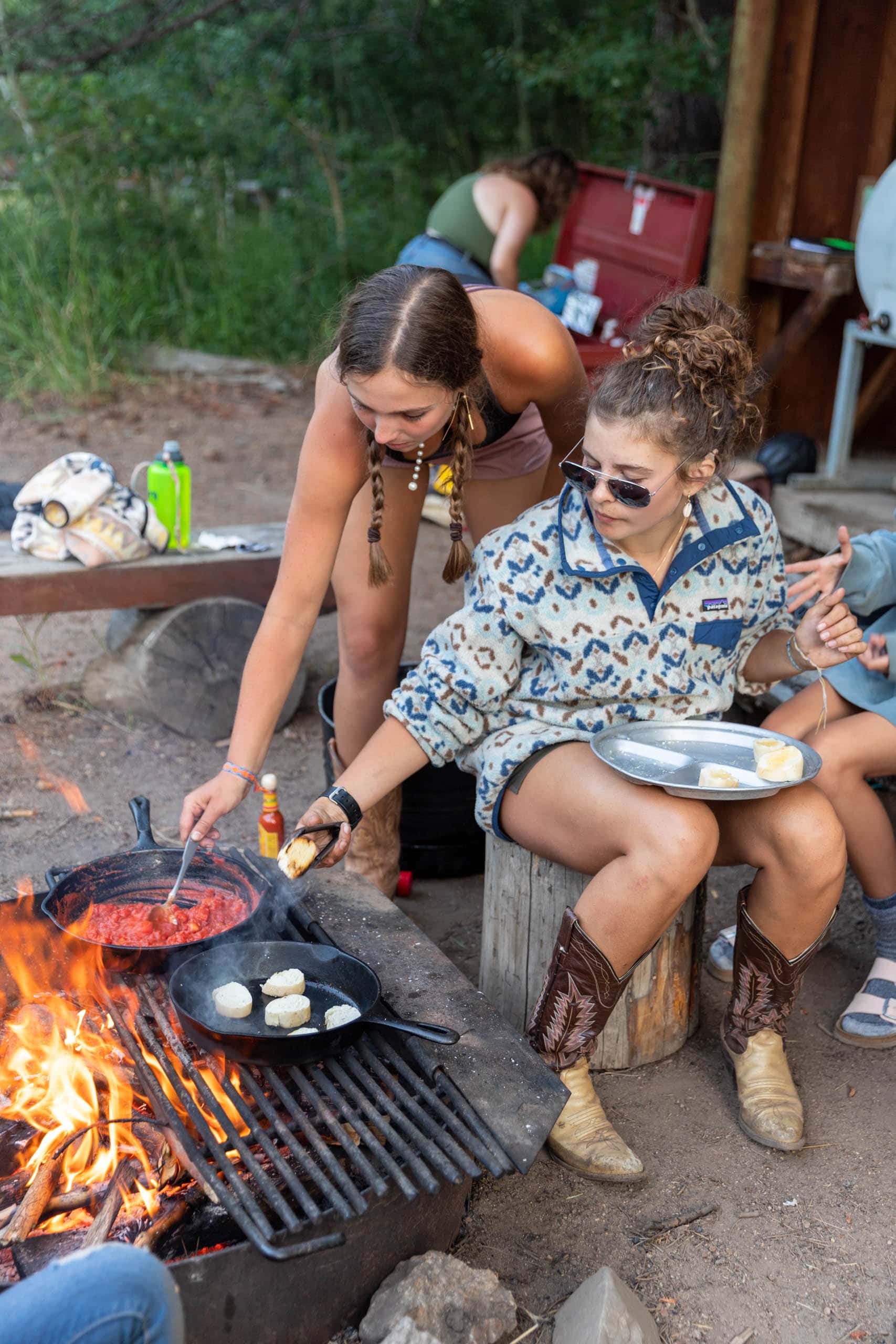 Campers cooking dinner over a fire.