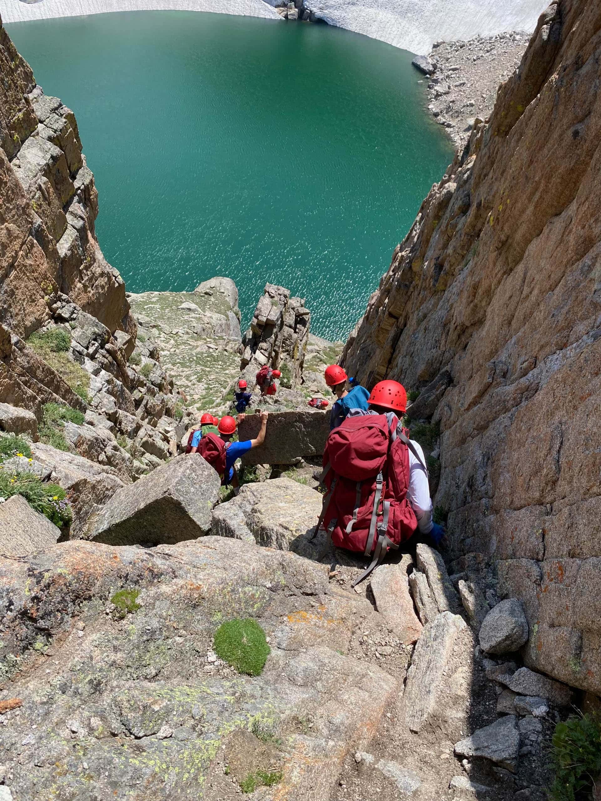Campers climbing down rocks on a backpacking trip.