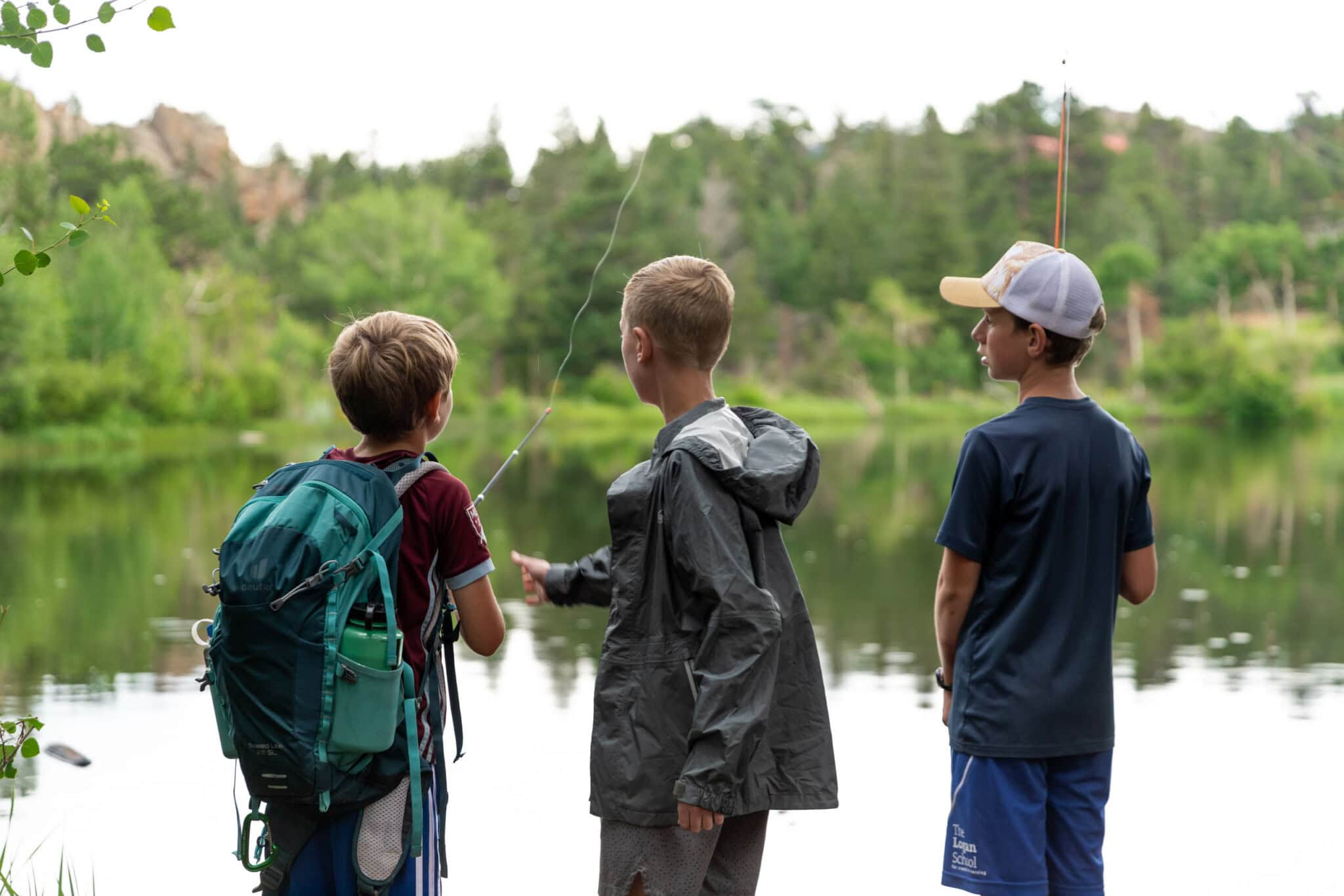 Campers on the riverbank with fishing poles.