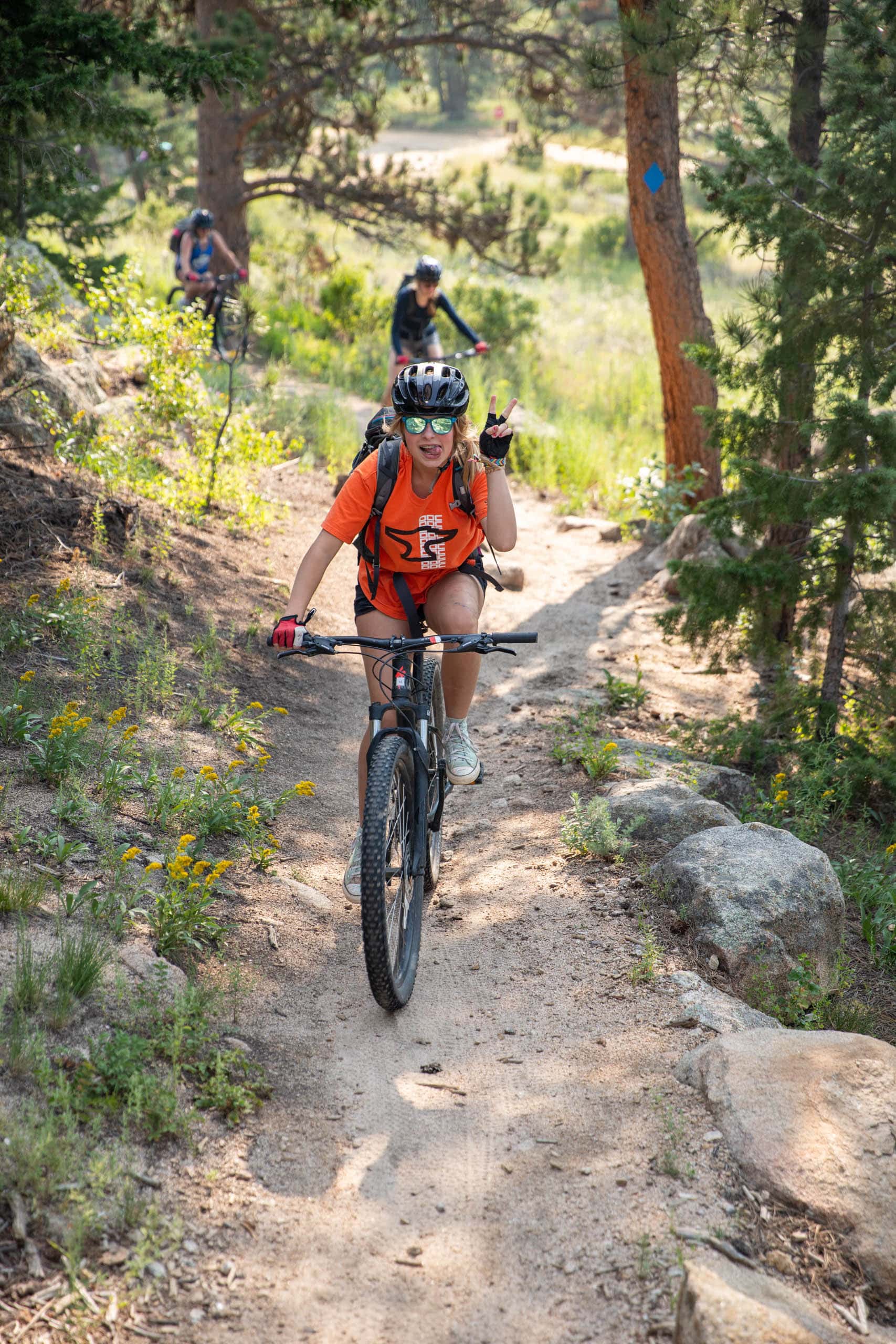 Camper giving a peace sign while riding on a mountain bike trail.