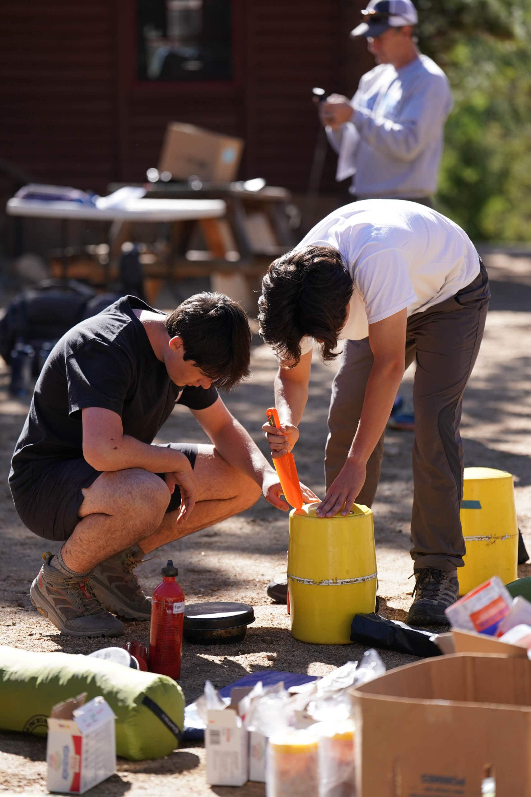 Campers preparing bear cans for a backpacking trip.