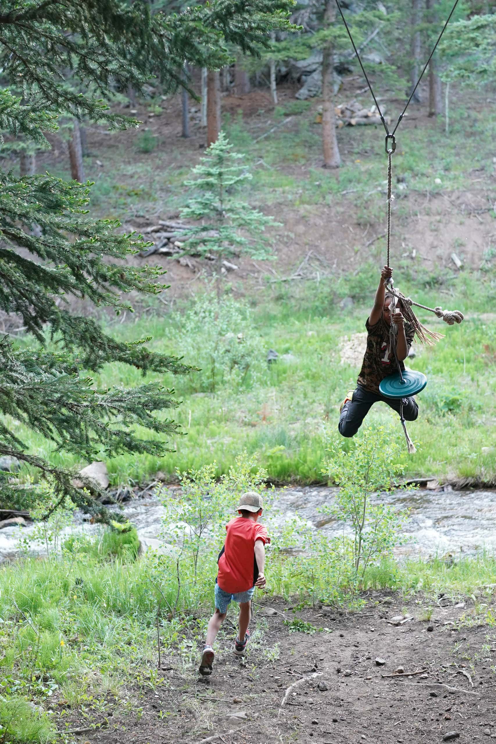 Camper swinging on a rope swing with a river in the background.